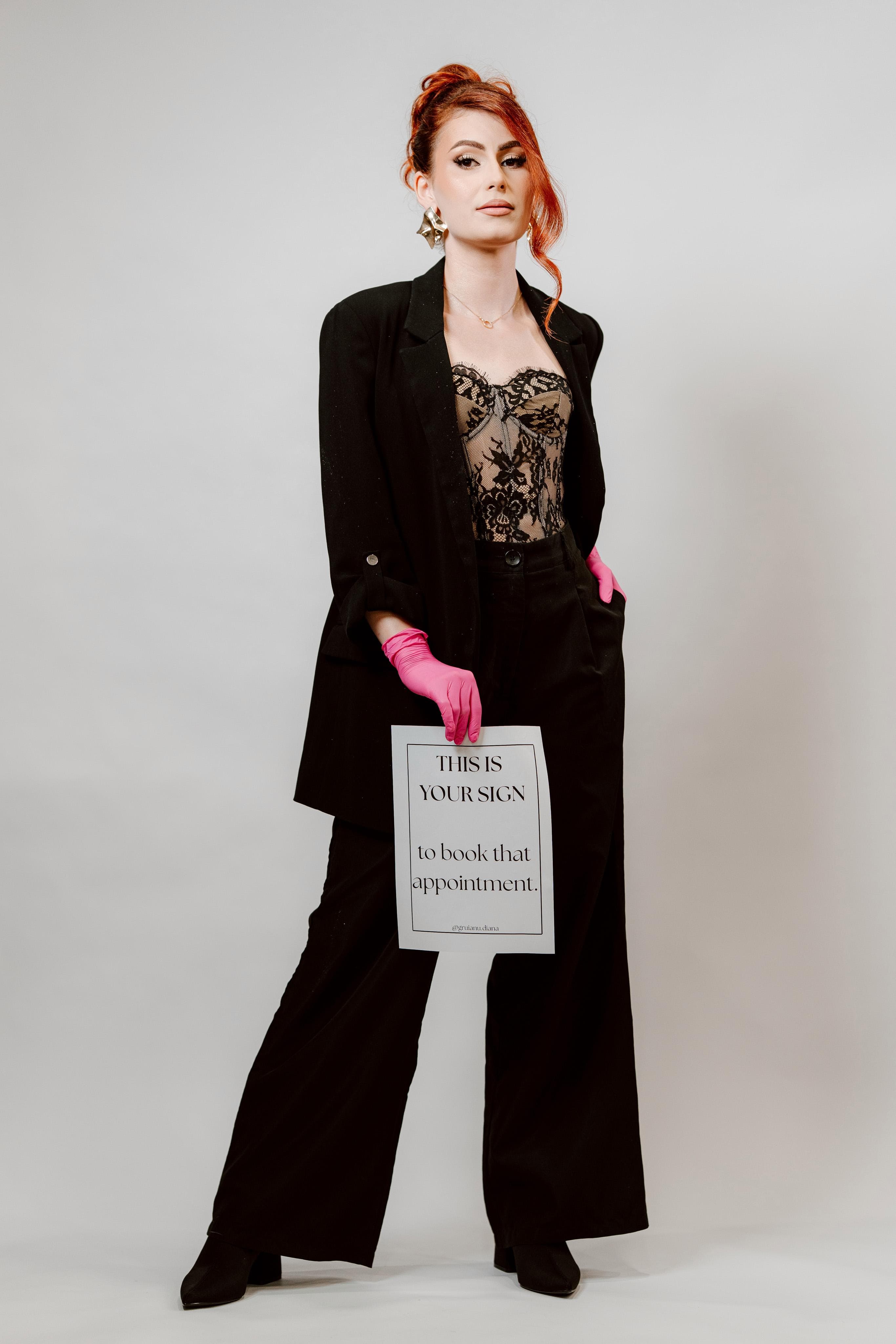 Diana Gruianu în costum negru, ținând un afiș pentru programări